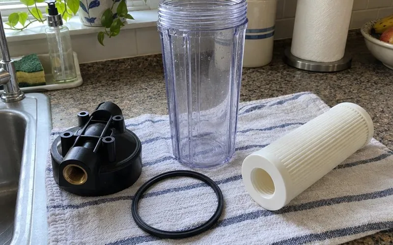 Cap, clear sump, O-ring and pleated cartridge of a 10 inch filter housing laid out on a counter