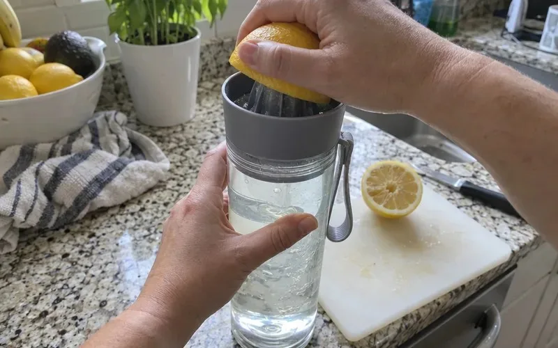 Lemon half pressed onto the built-in juicer of an infuser water bottle