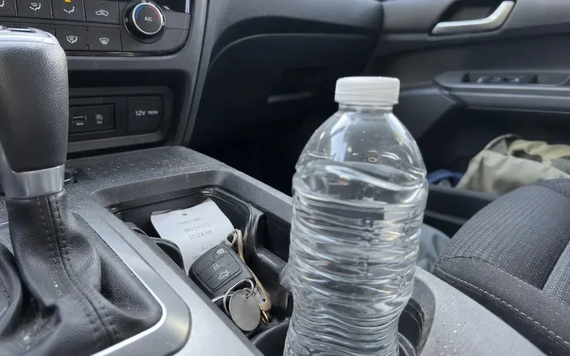 Standard plastic water bottle sitting in a car center console cup holder